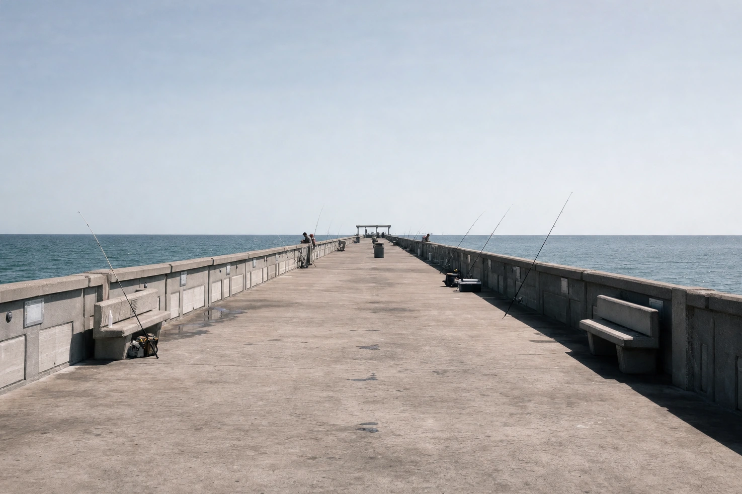Our photograph taken along the length of a concrete fishing pier at midday, even light, a few figures a long way off.
