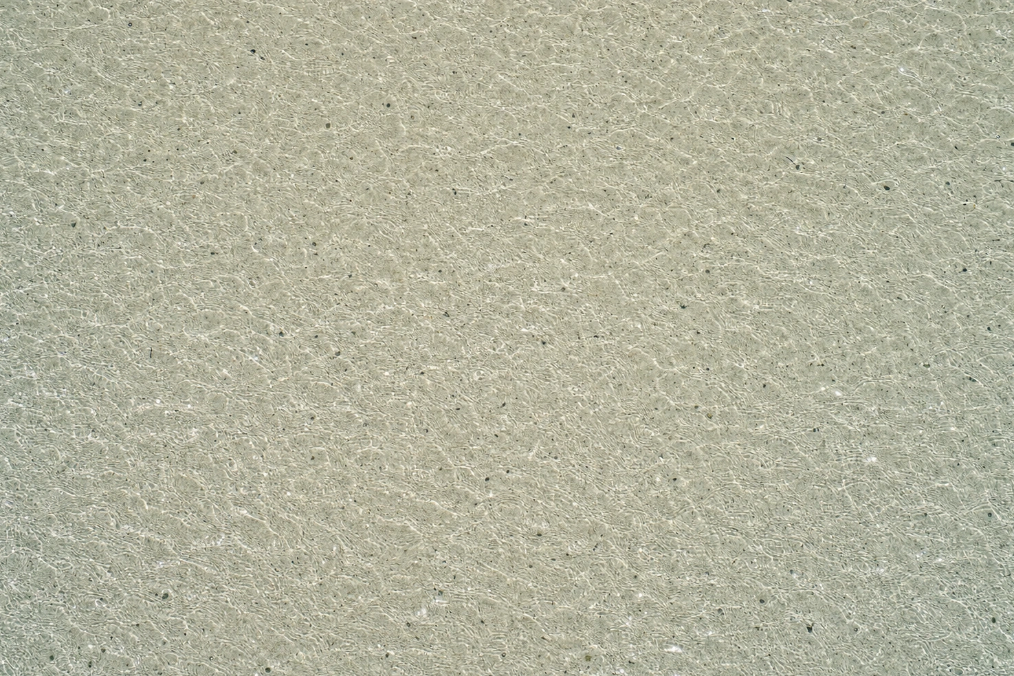 Our photograph looking straight down at flat shallow water filling the whole frame at midday, evenly rippled, nothing else in it.